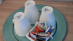Three white mugs on a teal plate with a box of Nestle Original Crunchy bars.