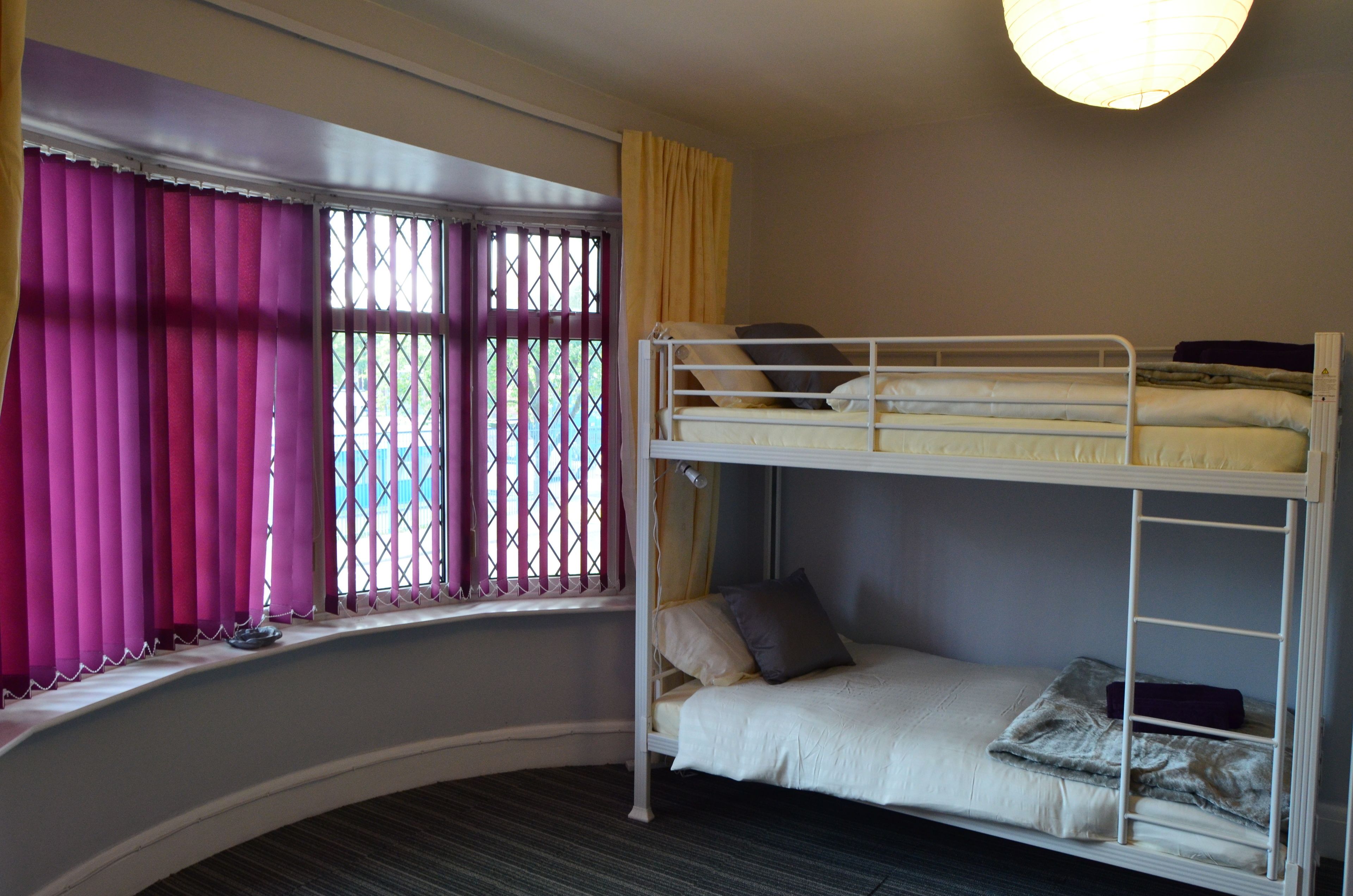 A bunk bed room with a window and curtains.