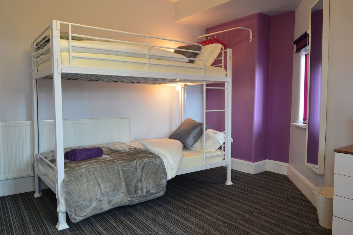 A bunk bed room with a window, a radiator, and a small shelf.