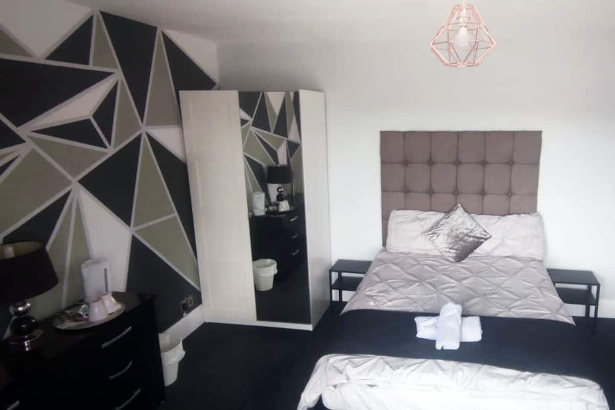 A modern bedroom with a large bed, a wardrobe, a bedside table, and a radiator.