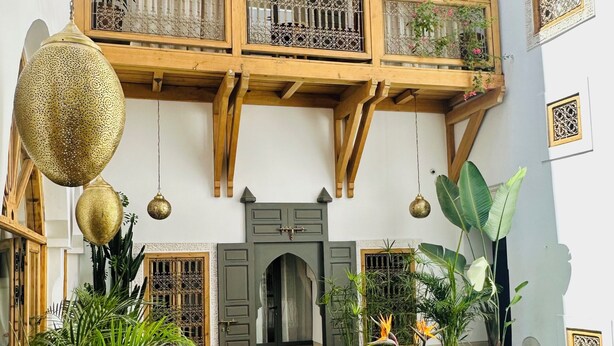 Un patio tradicional con balcón de madera, plantas en macetas, zona de estar y una pequeña piscina.