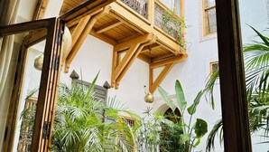 Una habitación con un ventanal grande, vigas de madera y plantas en macetas.