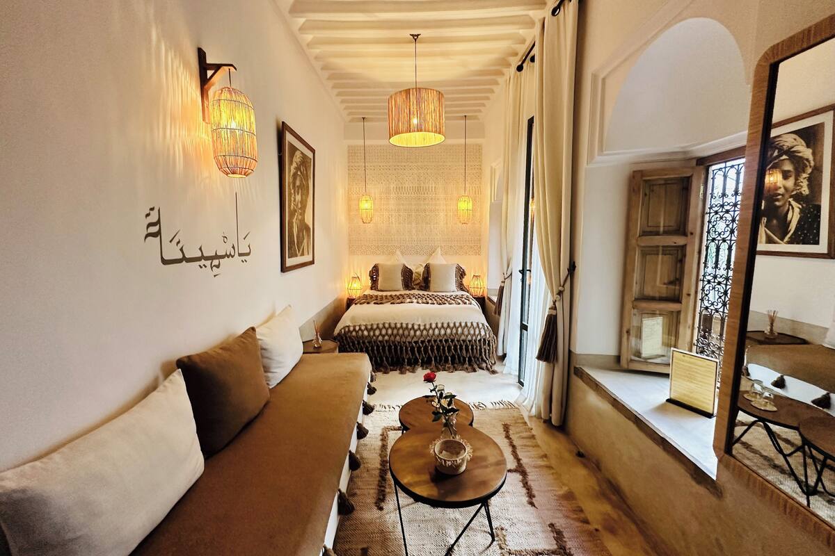 A cozy bedroom with a bed, a sofa, a coffee table, and a window with a view.