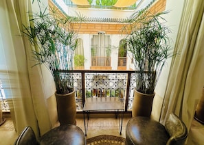 A balcony with two potted plants, a table, and two chairs. - Riad le Jardin Des Sens (Marrakech)