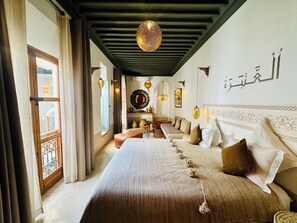 Habitación de hotel con una cama grande, un área de estar y vistas por la ventana.