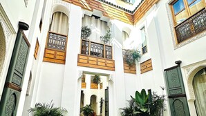 Un patio con piscina, plantas en macetas y elementos arquitectónicos tradicionales.