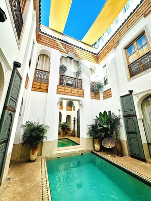 Un patio con piscina, plantas en macetas y elementos arquitectónicos tradicionales.