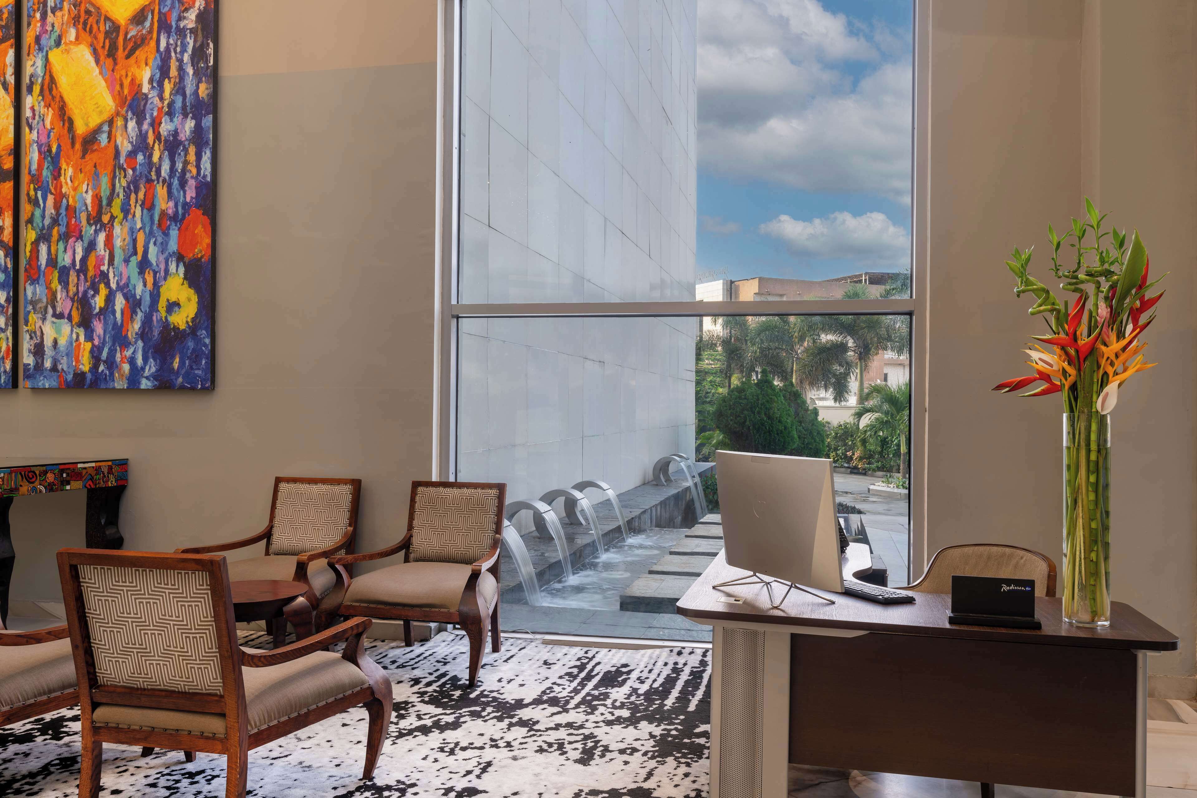 A modern hotel lobby with a large window, a desk with a computer, and two chairs.