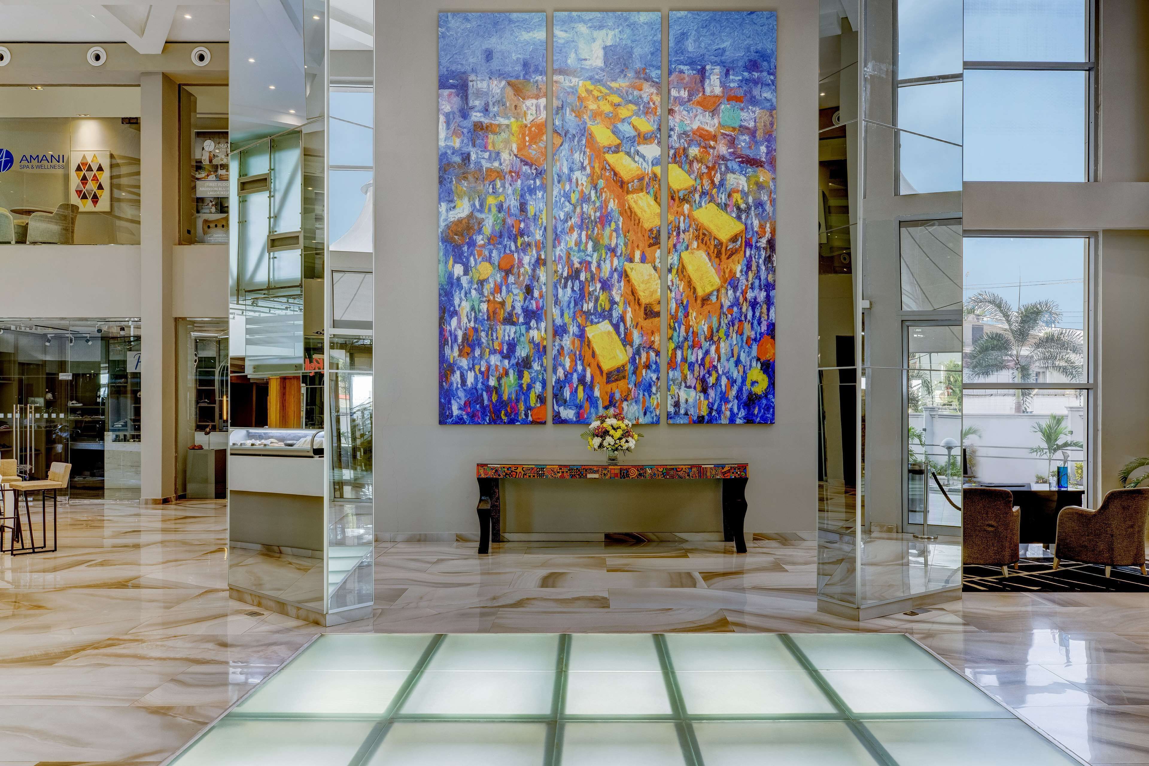 A spacious lobby with a large abstract painting, a marble floor, and a reception desk with chairs.