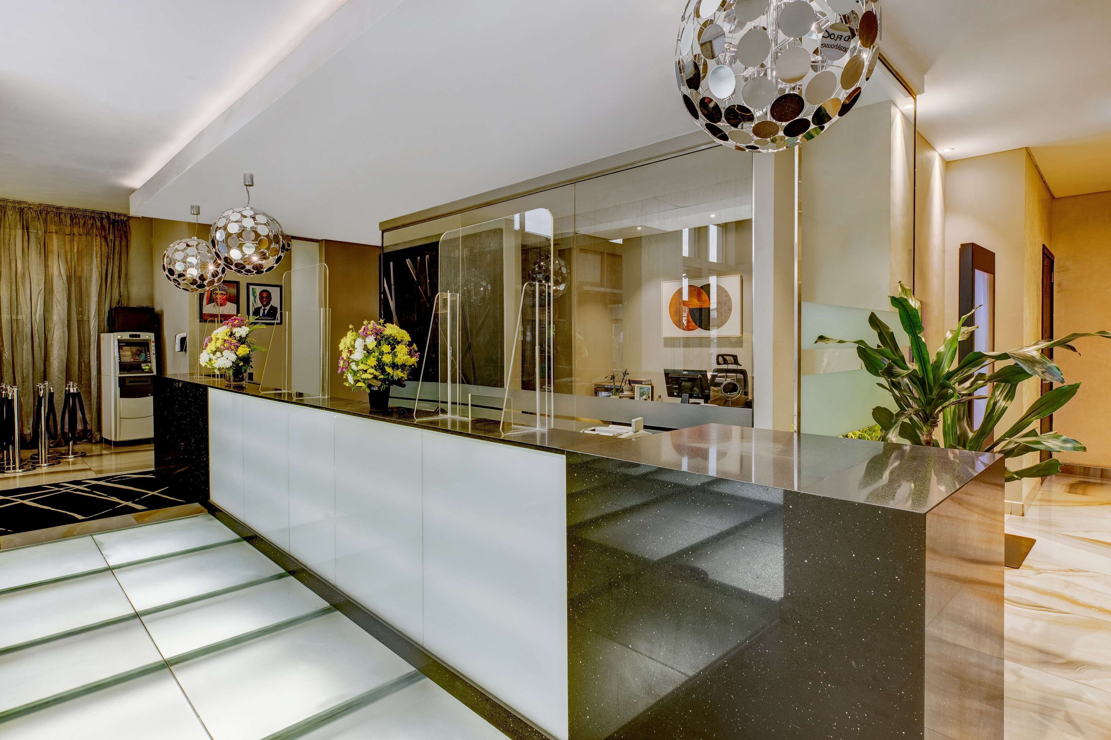 A modern kitchen with a glass partition, stainless steel appliances, and decorative plants.