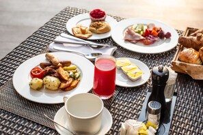 A breakfast setting with plates of food, a glass of red juice, and a cup on a woven table. - Radisson Blu Lagos Ikeja Hotel (Lagos)