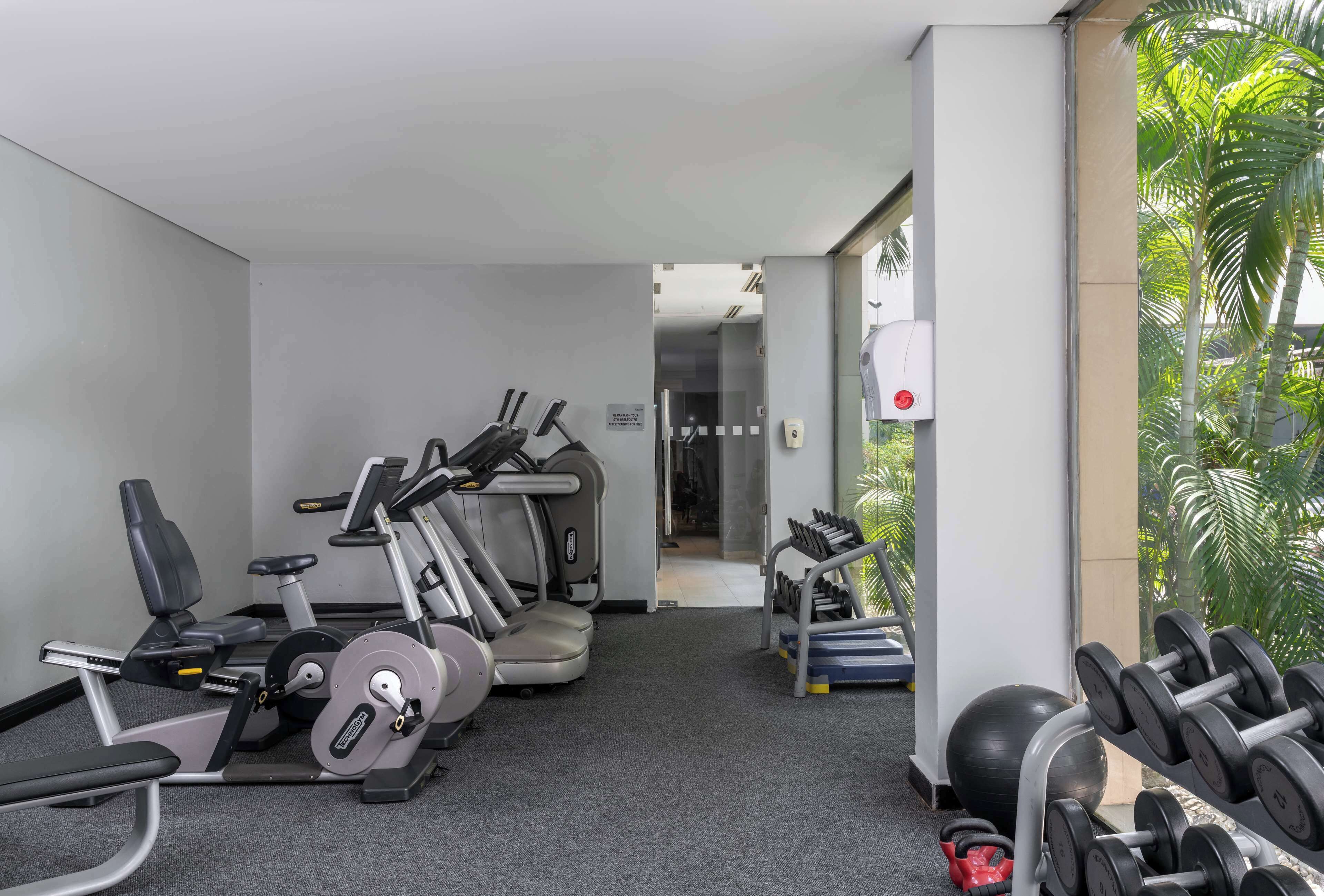 A gym with cardio machines, dumbbells, and exercise balls.
