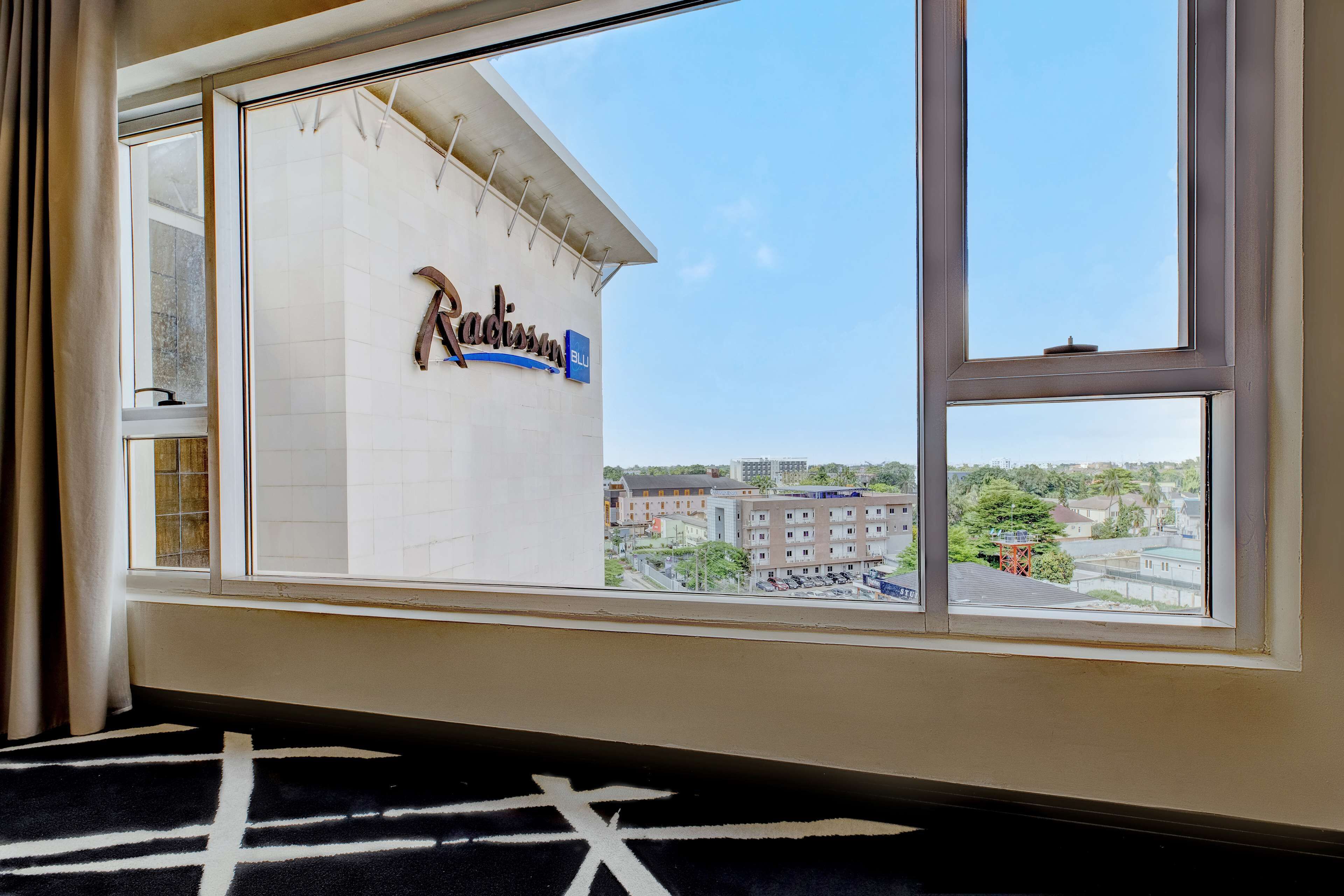 A room with a large window overlooking a building with a sign that reads "Radisson Blu".
