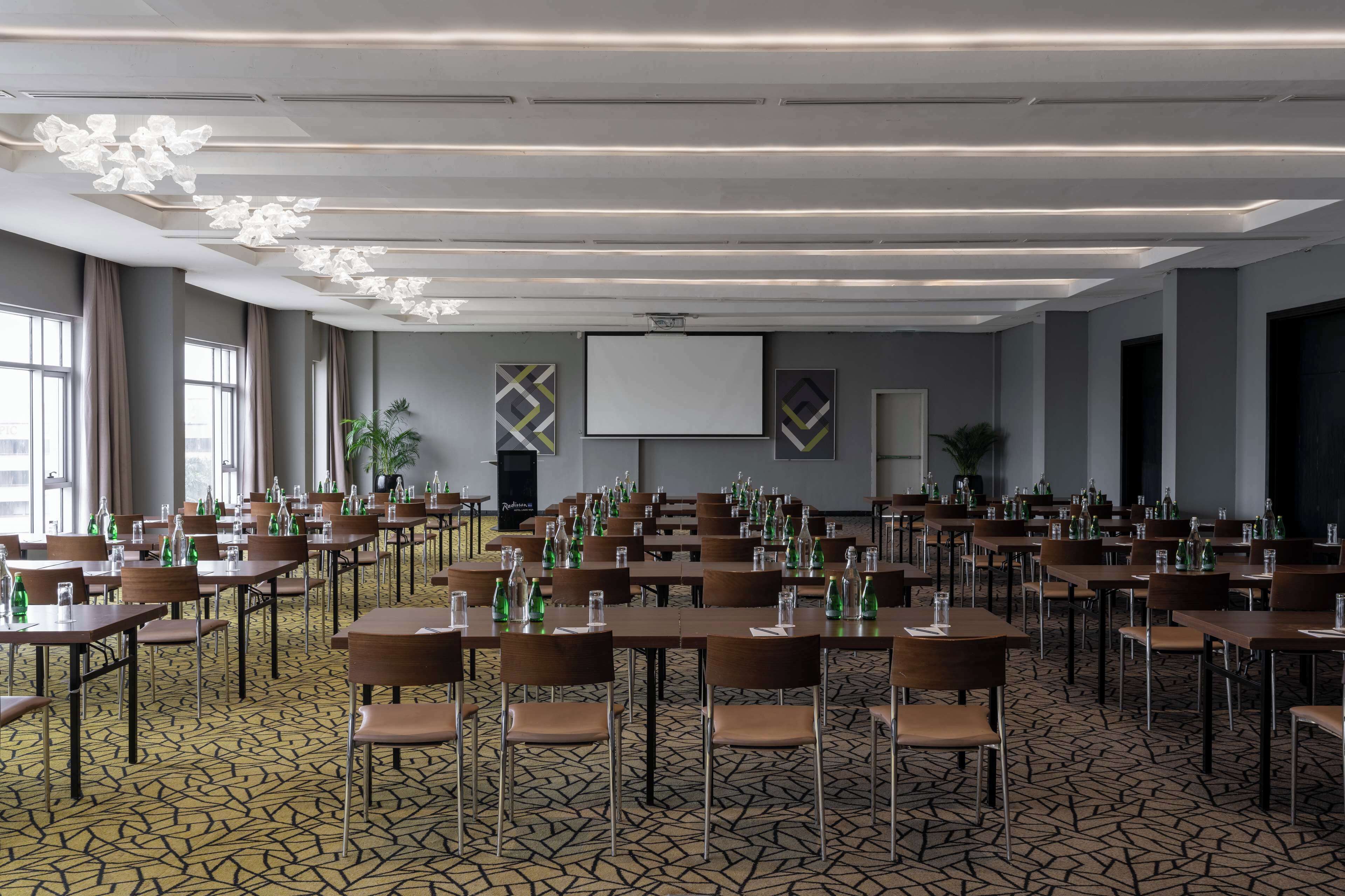 A conference room with tables, chairs, and a projector screen.