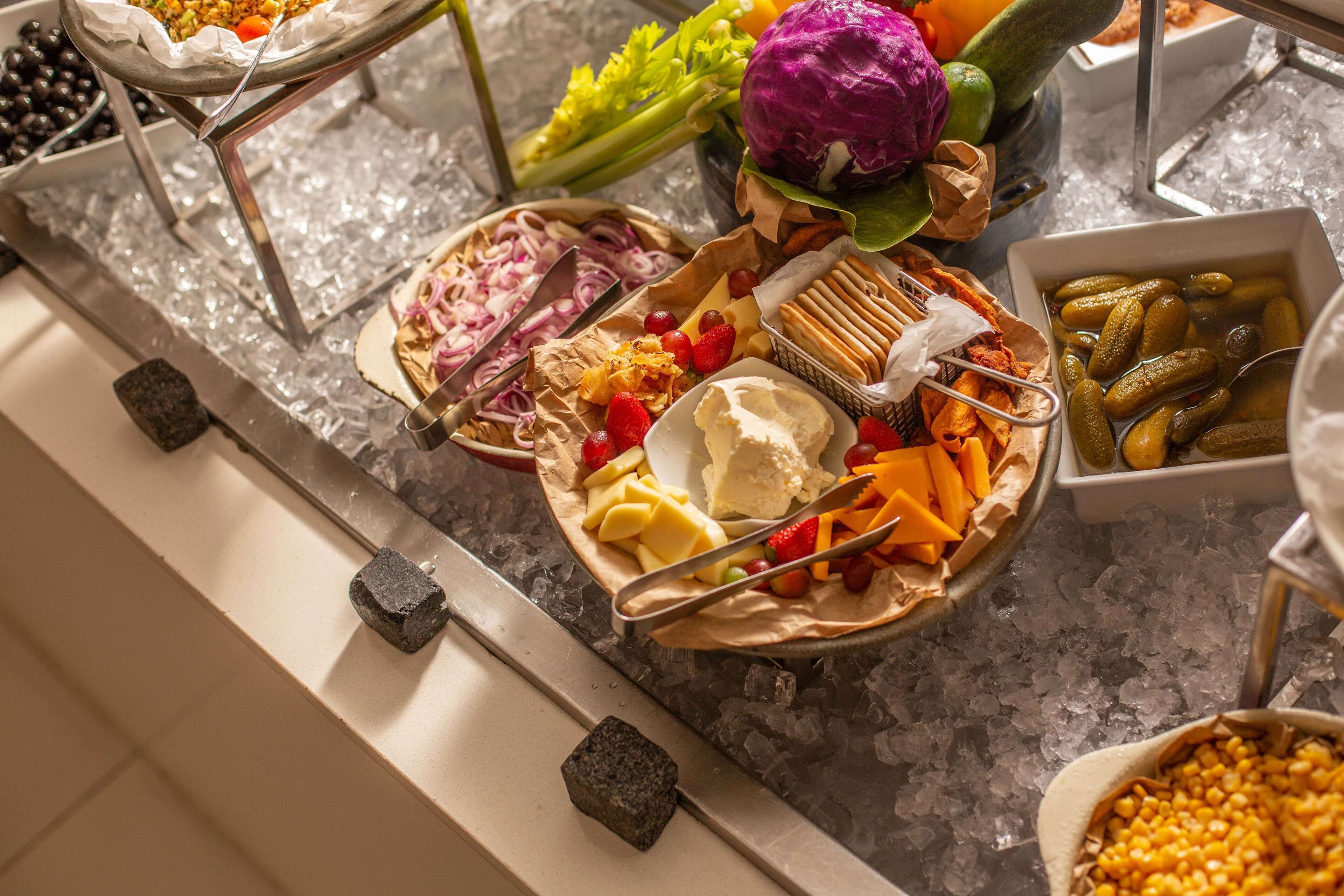 A buffet with various food items like fruits, vegetables, and cheeses on ice.