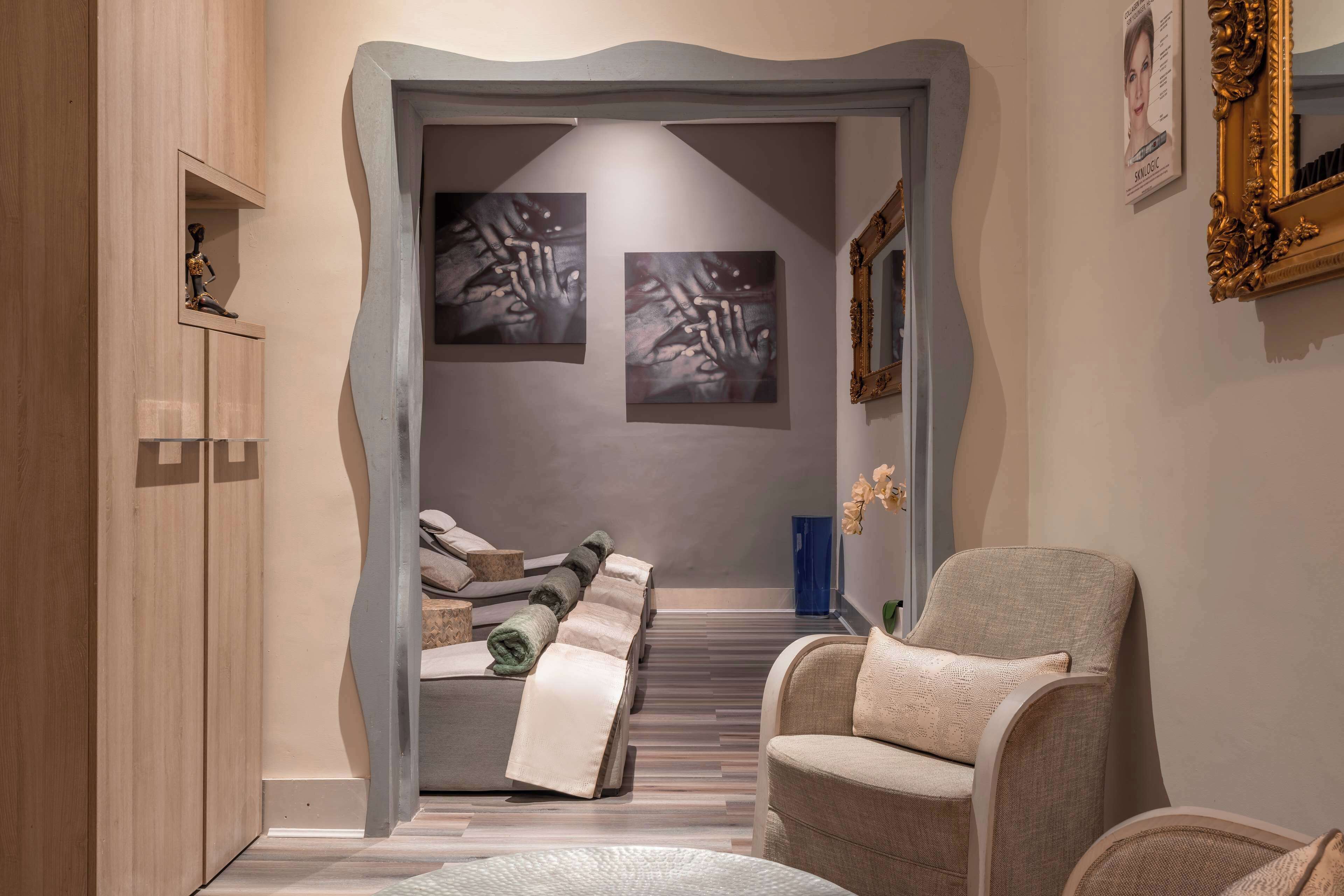 A modern hotel lobby with a unique architectural archway, a comfortable seating area, and artwork on the walls.