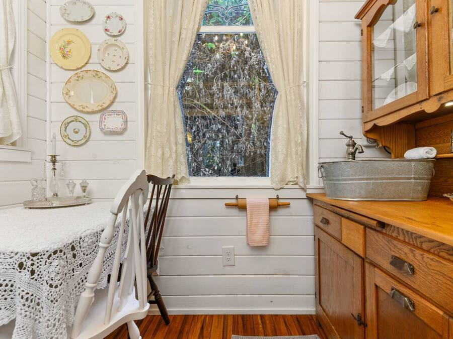 Una cocina rústica con armarios de madera, un lavamanos y una ventana con cortinas de encaje.