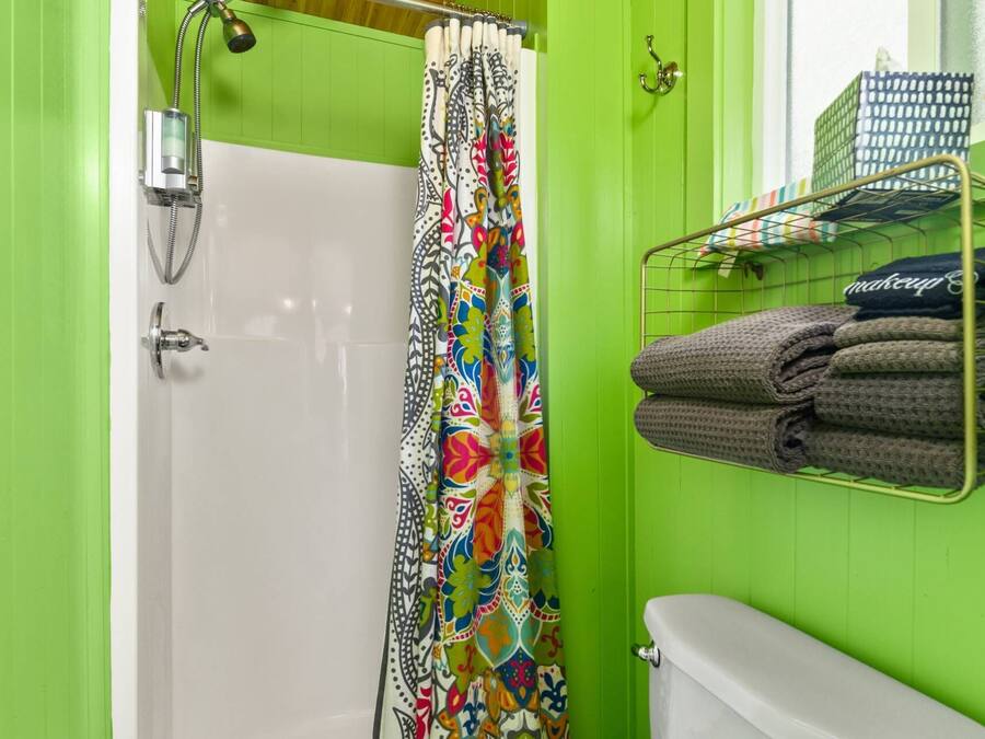 A bathroom with a shower, toilet, and a towel rack with folded towels.