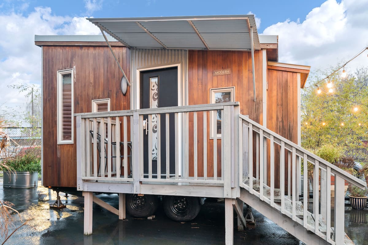 A wooden cabin with a balcony and a ramp leading to the door.