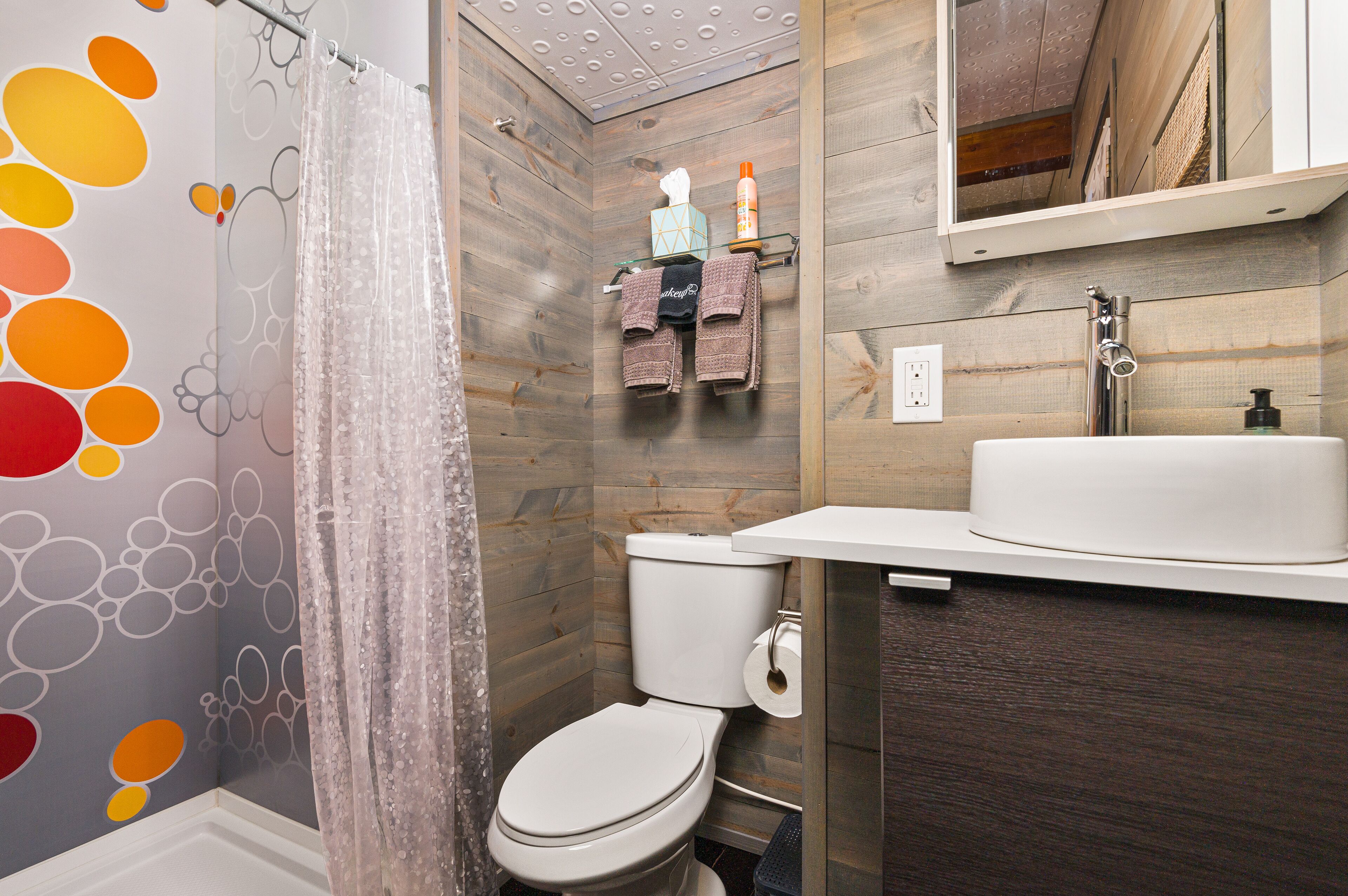 Ein Badezimmer mit Holzwand, Waschbecken in Weiß und Toilette.