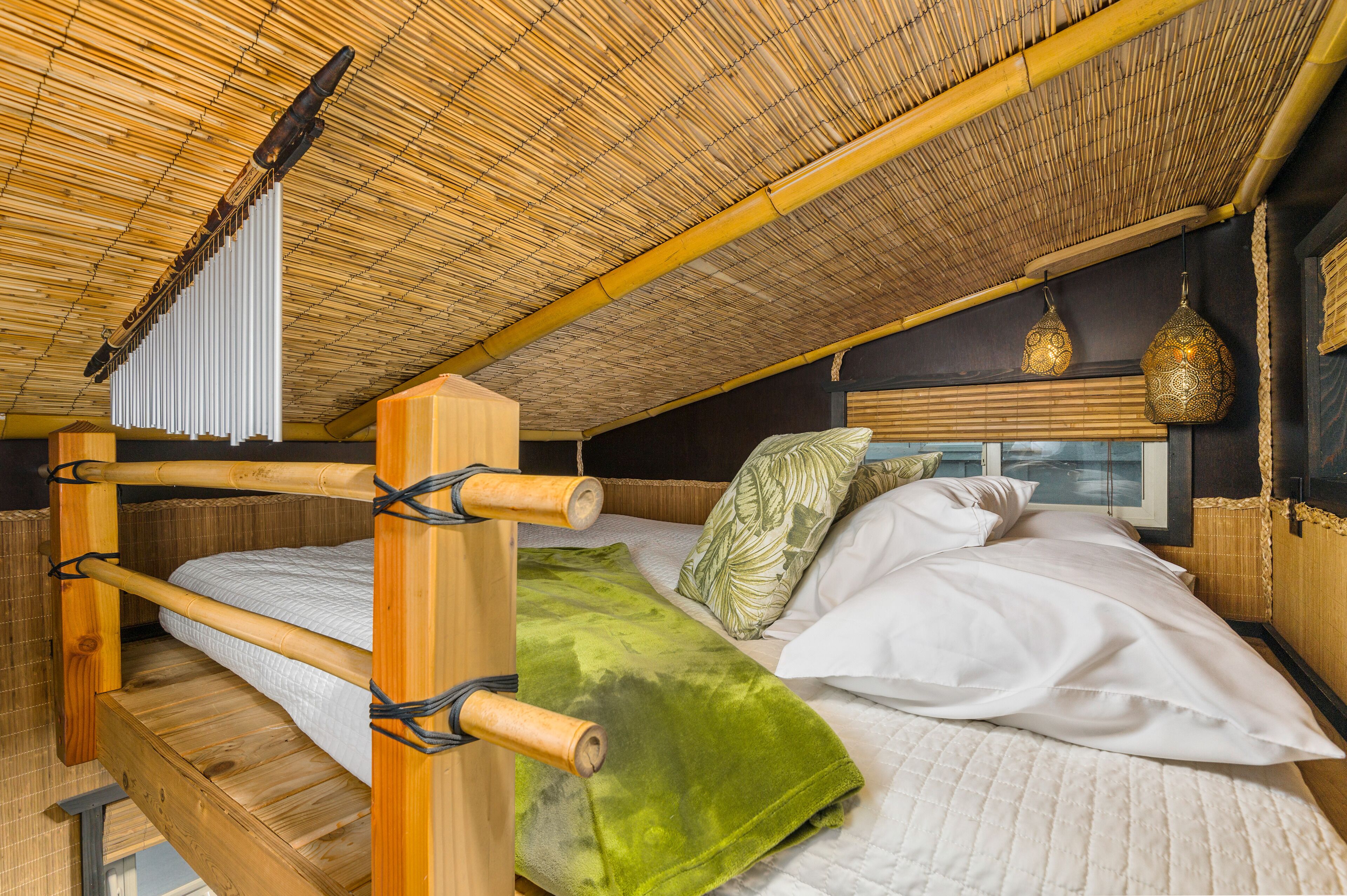 Ein Zimmer mit Bambusdecke, Etagenbett und einem Fenster mit Jalousien.
