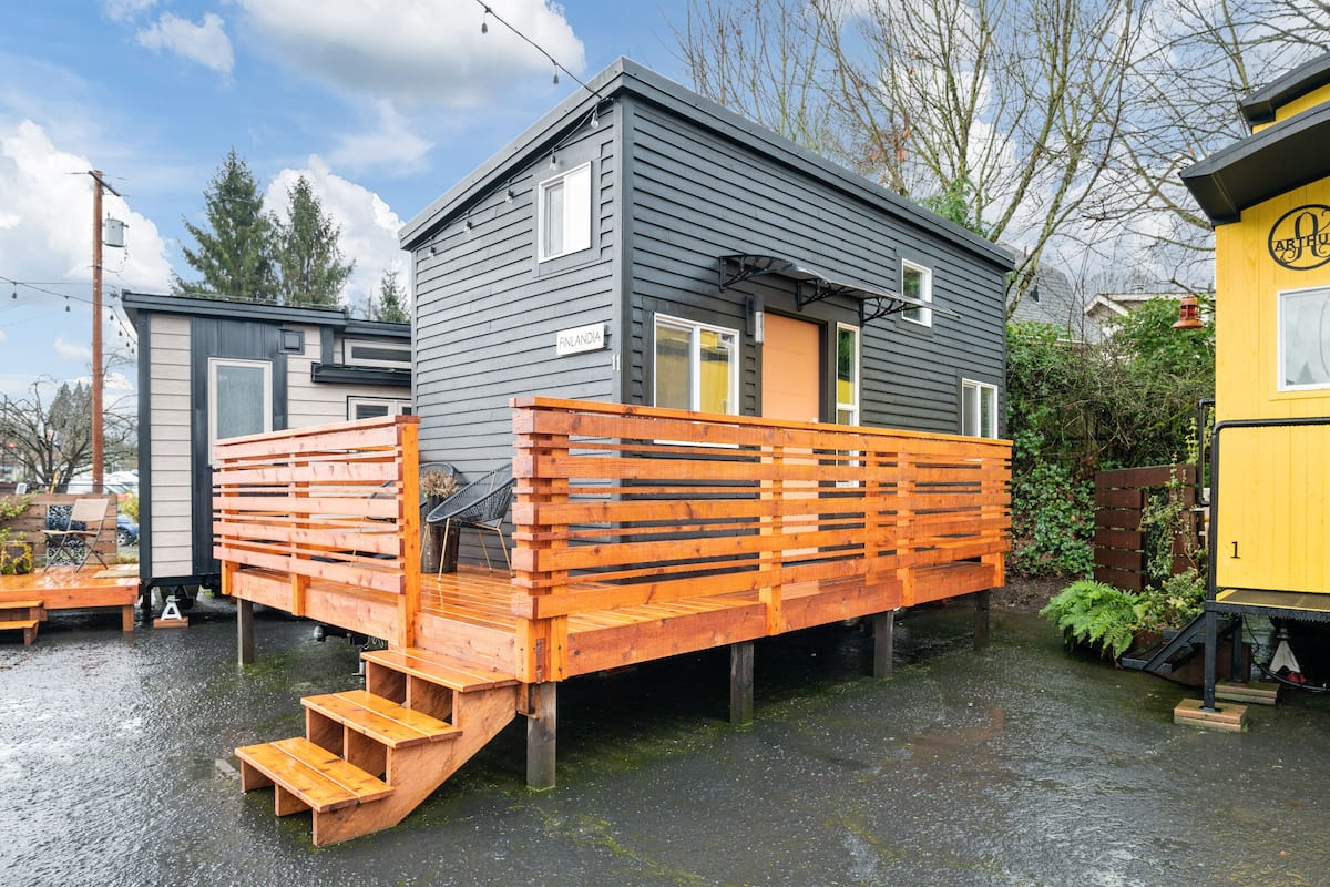 A small, two-story house with a wooden deck and steps leading to the entrance.