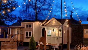 A small wooden house with a porch, a small shed, and string lights. - Tiny Digs - Hotel of Tiny Houses (Portland)