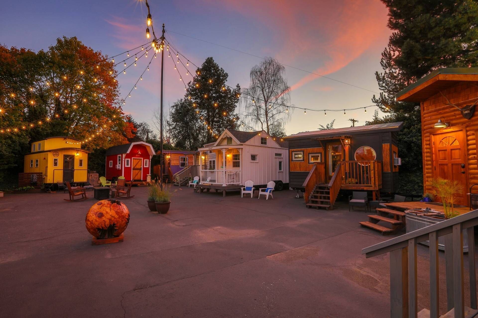 A rustic cabin-style lodging area with multiple small cabins, outdoor seating, and a large decorative pumpkin.