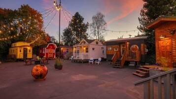A rustic cabin-style lodging area with multiple small cabins, outdoor seating, and a large decorative pumpkin.
