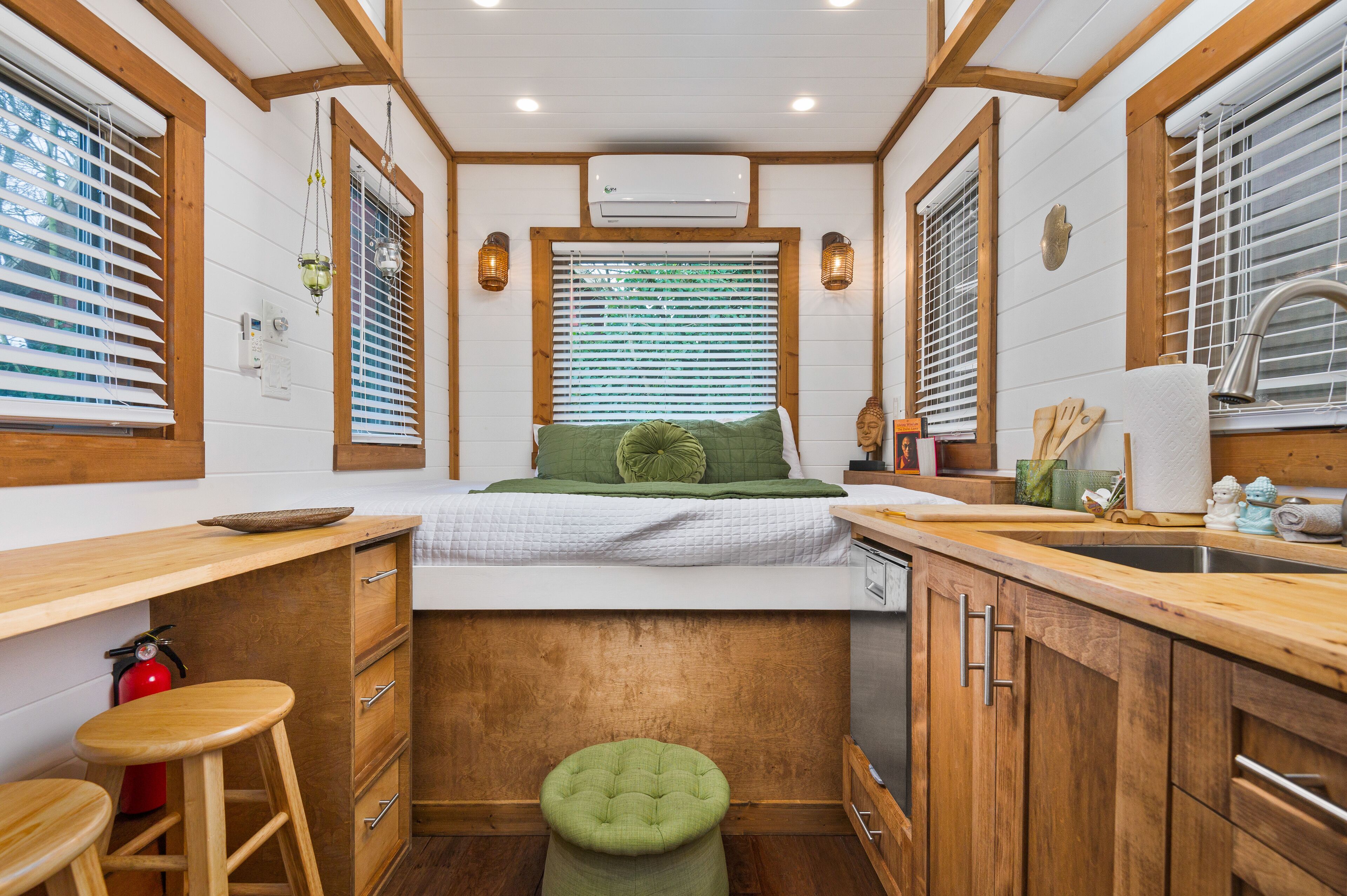 A compact kitchen with wooden cabinets, a countertop, a sink, and a window with blinds.