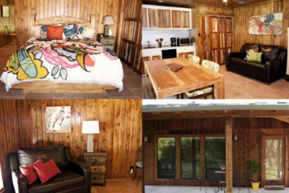 A wooden interior with a bed, a dining area, a living room with a sofa, and a large window.