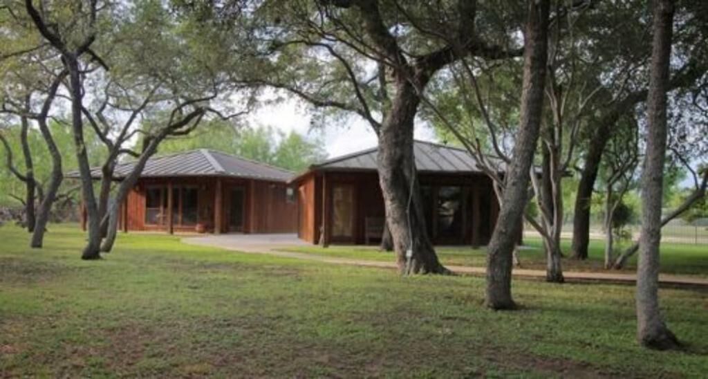 A cabin with a metal roof, surrounded by trees and a grassy area.
