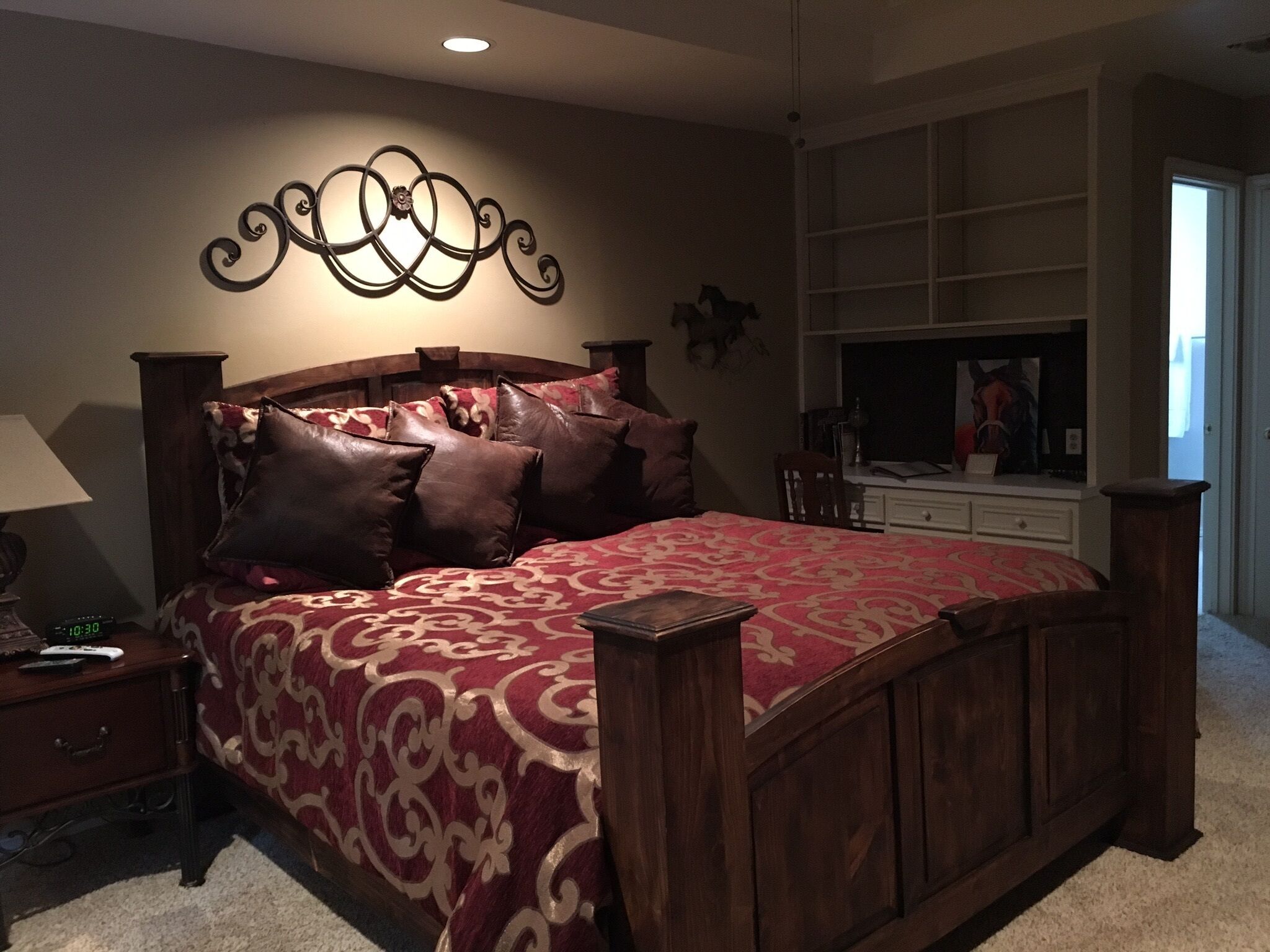 A bedroom with a large bed, wooden headboard, and a decorative wall piece.
