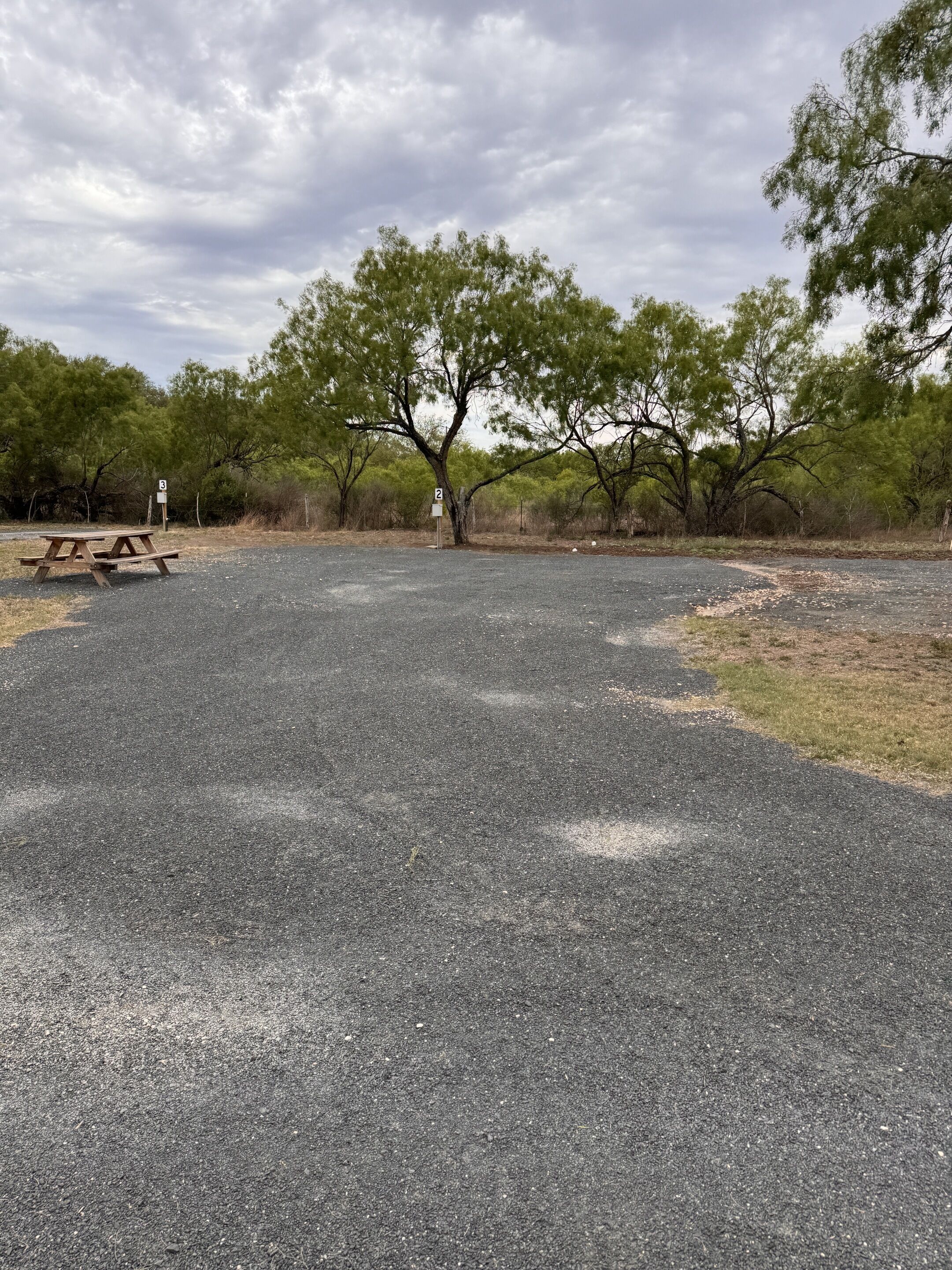 A picnic area with a picnic table and two numbered signs, surrounded by trees.