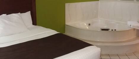 Ein Hotelzimmer mit einem großen Bett, einer separaten Badewanne und grünen Wänden.