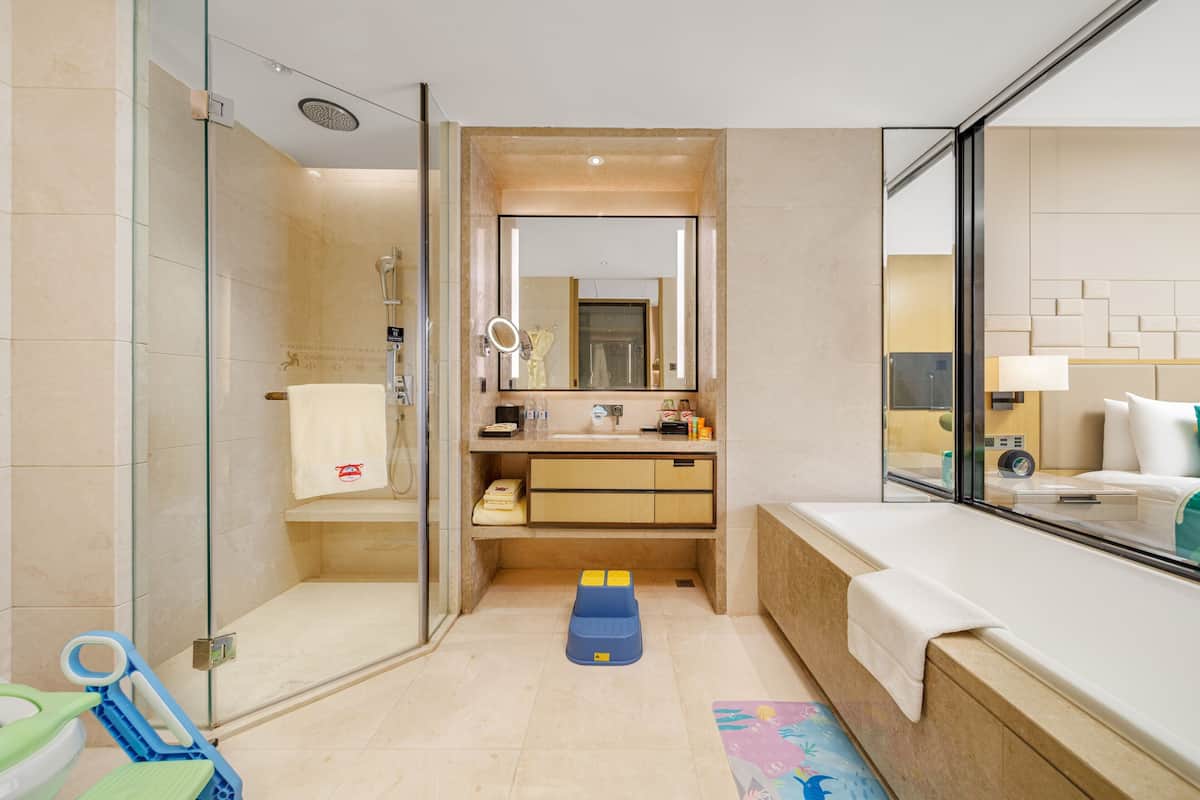 Un bany modern amb plat de dutxa de vidre, un lavabo amb mirall i una banyera.