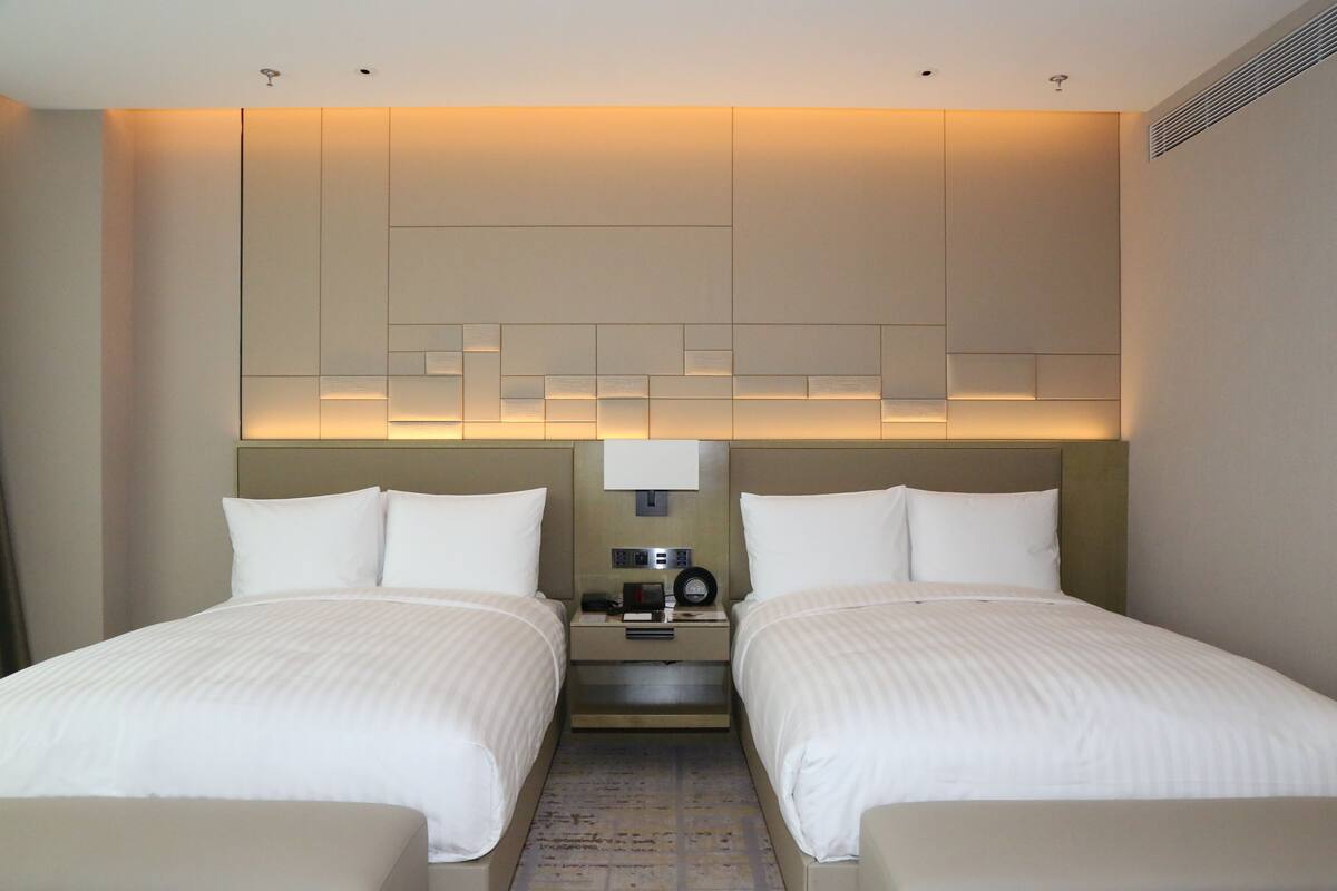Ein Hotelzimmer mit zwei Betten, einem Nachttisch mit Lampe und einer Wandleuchte.