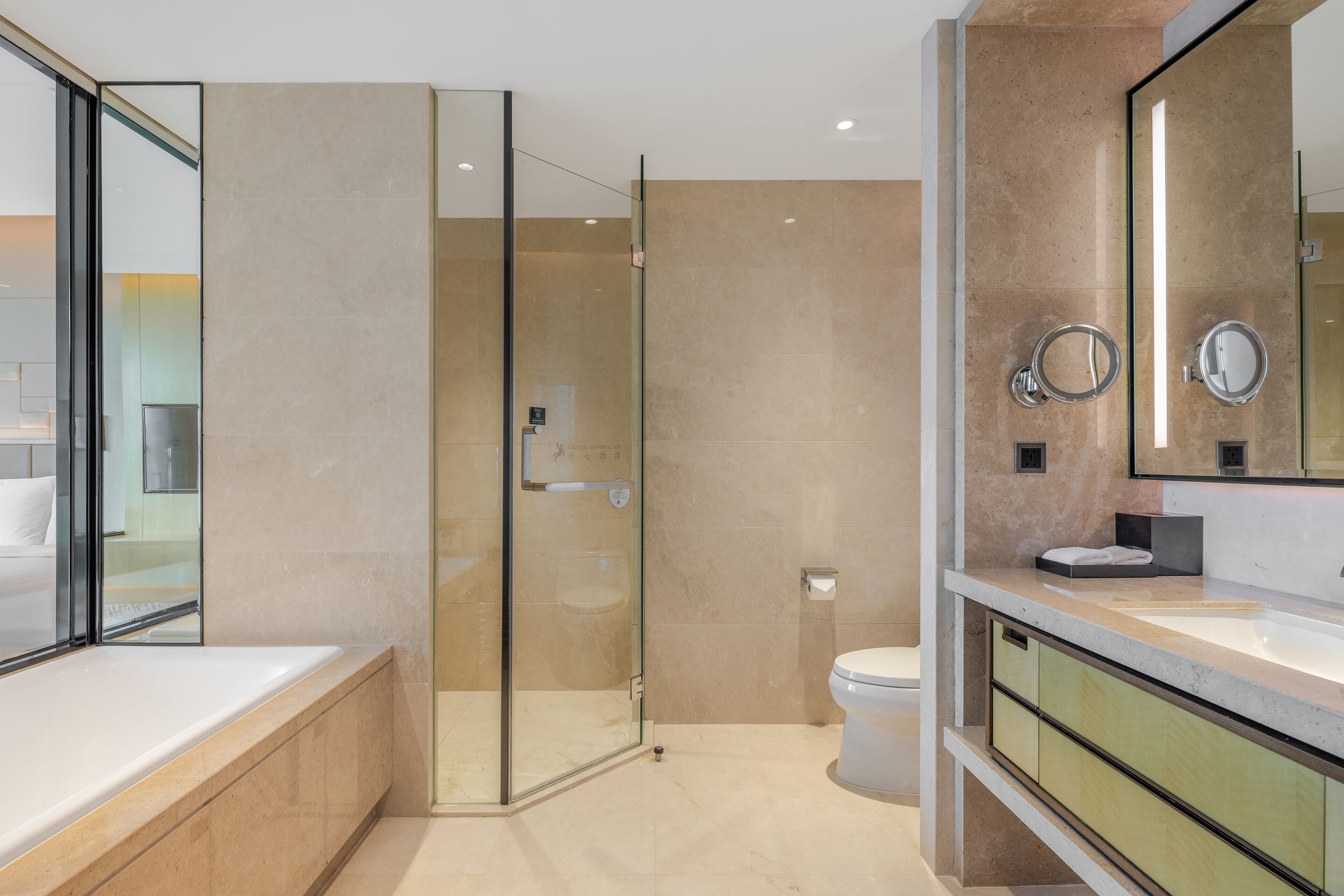 A modern bathroom with a glass-enclosed shower, a large mirror, and a vanity with a sink.