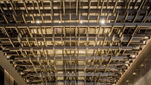 Un intérieur moderne avec un plafond au design géométrique, un sol en marbre poli et une colonne centrale.