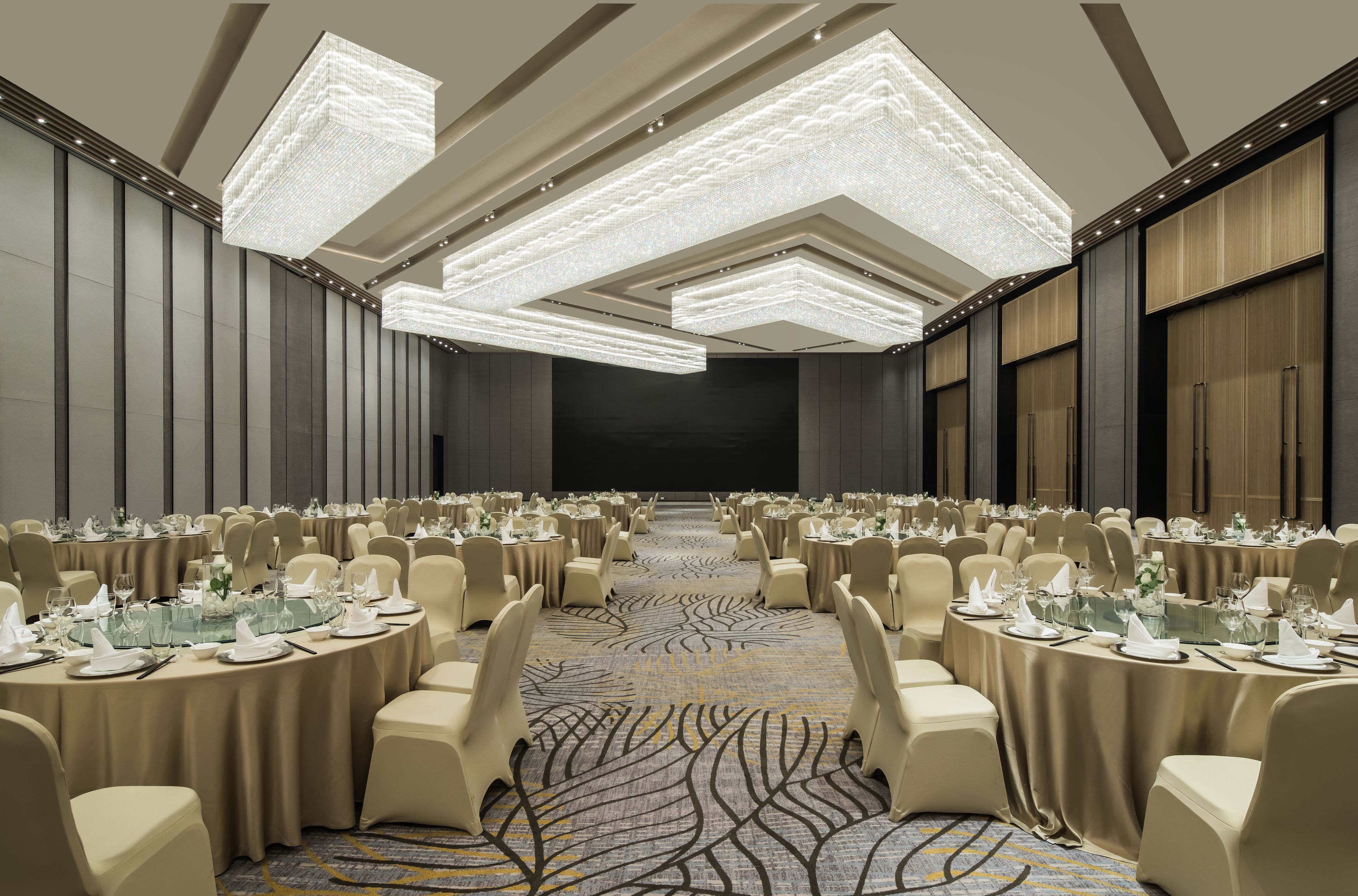 A conference room with round tables, beige chairs, and a patterned carpet.