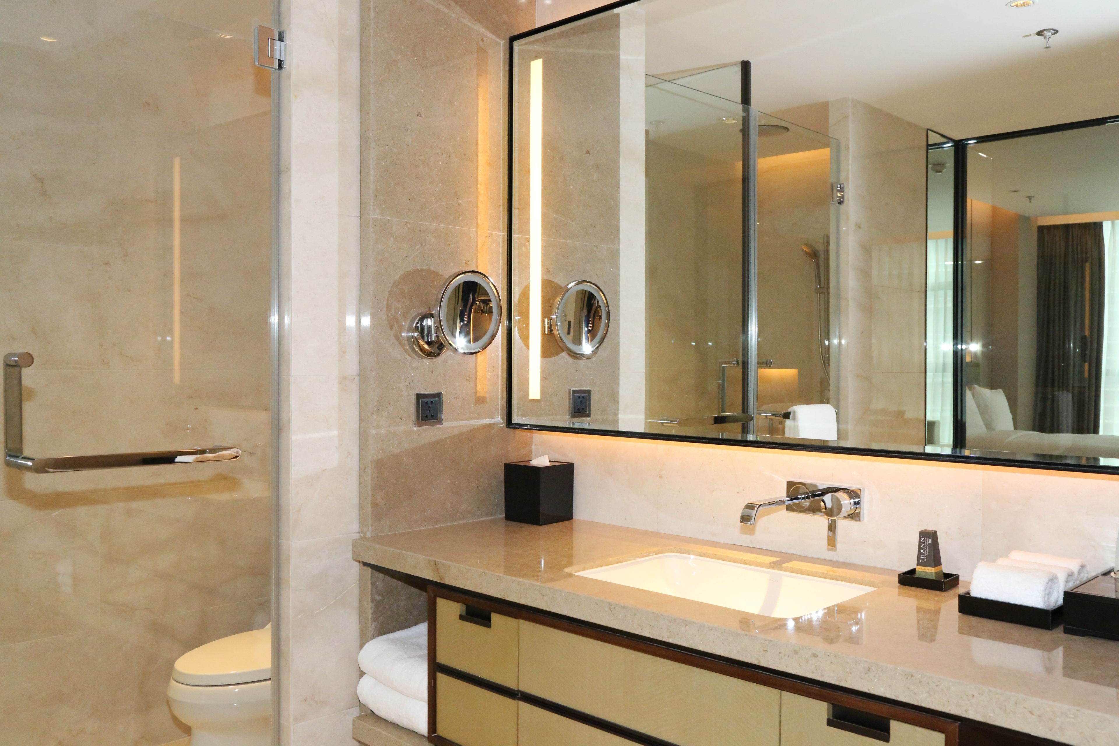 A modern bathroom with a large mirror, a sink, and a toilet.