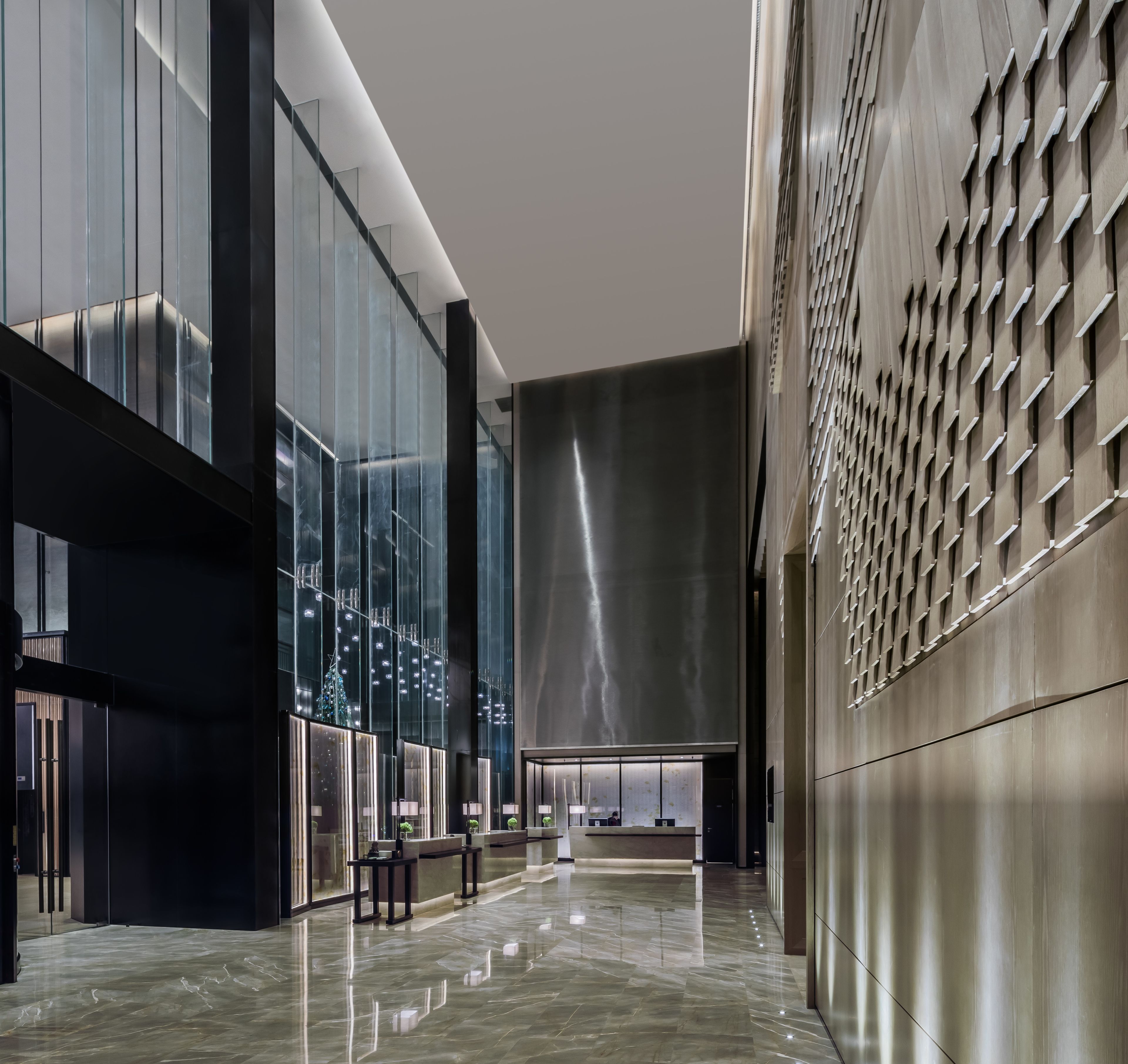 A modern lobby with reflective floors, glass walls, and a patterned wall.