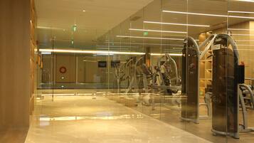 A modern gym with glass walls, exercise equipment, and a polished floor.