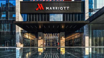 A modern Marriott hotel entrance with a reflective black floor, large glass windows, and a prominent red logo.