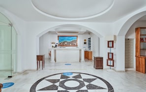 Experience the elegant lobby with a central reception desk, patterned floor, and arched doorways.