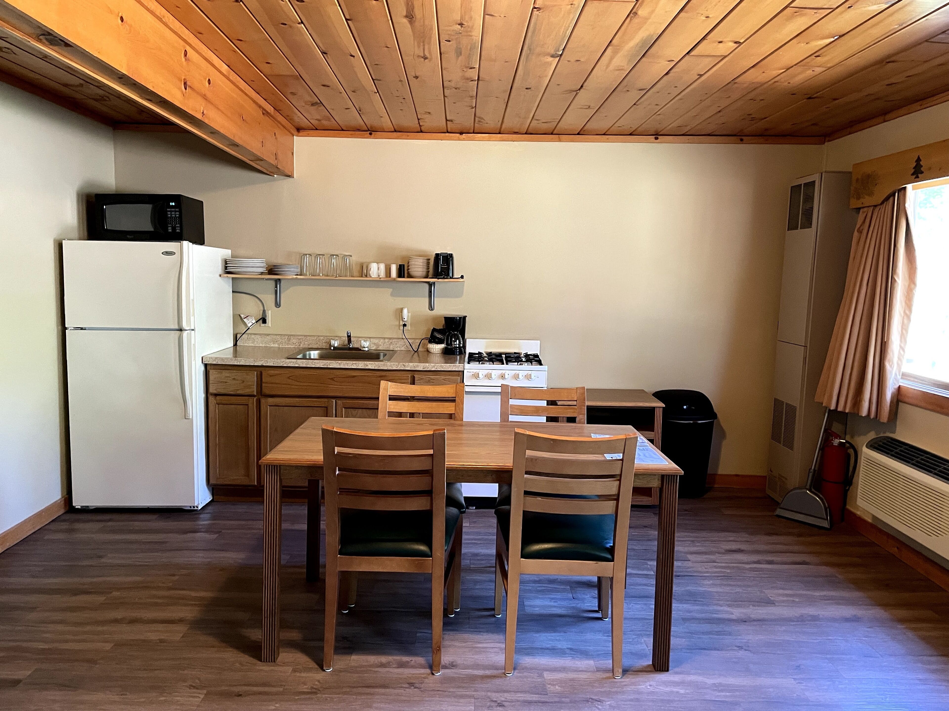 Una cucina funzionale con frigorifero, fornello e microonde. Ci sono due sedie di legno e un tavolo.