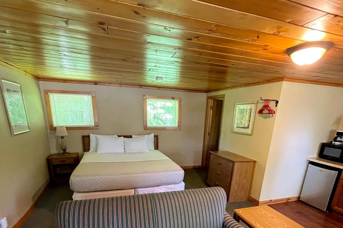 A cozy room with a bed, a striped sofa, a small table, and a kitchenette area.