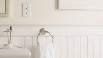 A bathroom with a white sink, a towel ring, and a small round table with toiletries.