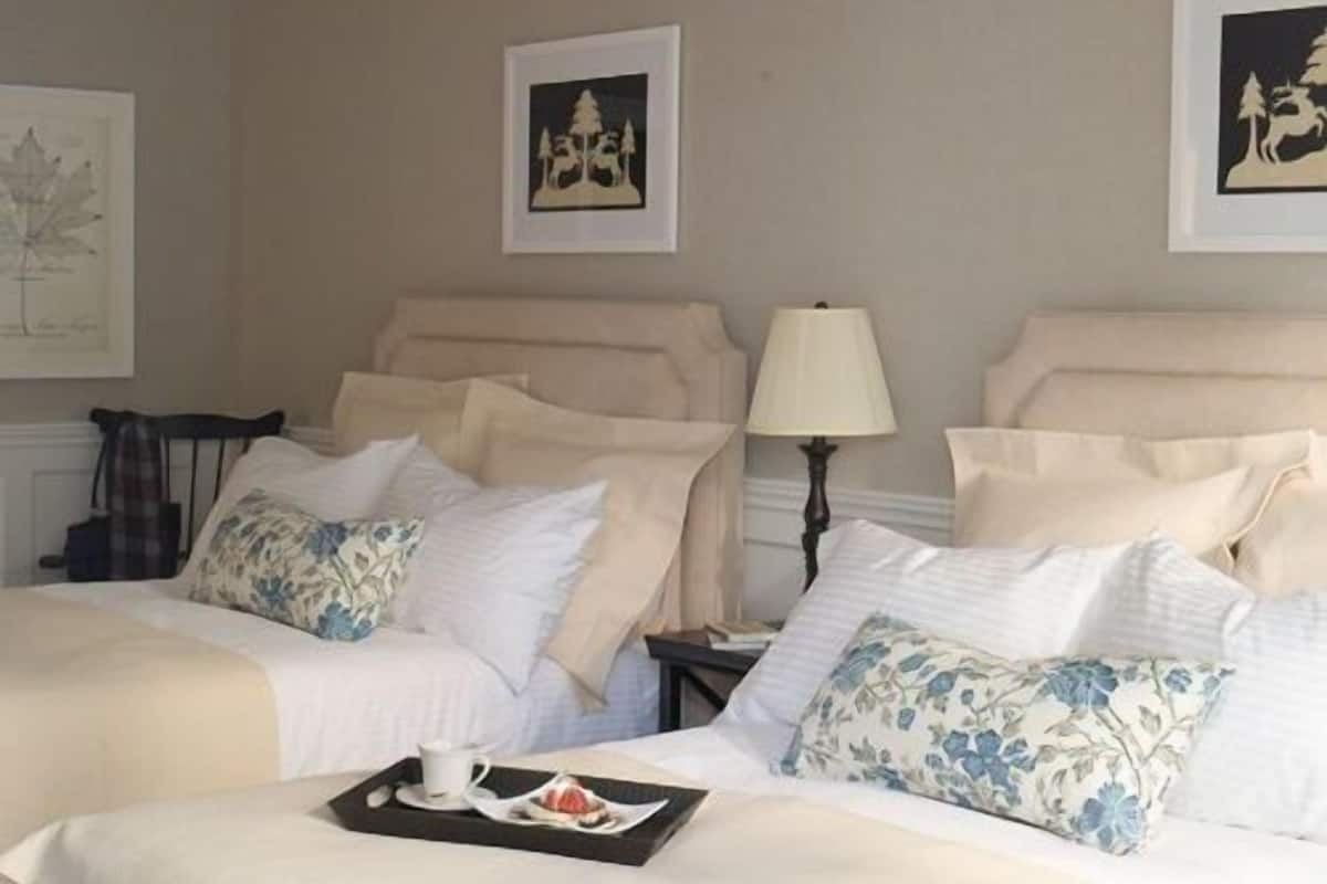 A neatly made bed with a tray of breakfast items, a lamp, and framed artwork on the wall.