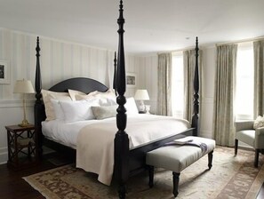 A four-poster bed with white linens, a matching bench, and two bedside tables with lamps. - The White Hart (Salisbury)
